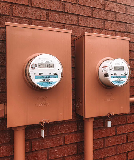Two orange Milbank meter sockets mounted on the side of a brick wall.